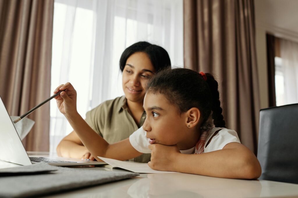 Empregos que Podem Deixar de Existir com a IA e Como se Proteger Mother and daughter engaged in online learning at home, using a laptop.