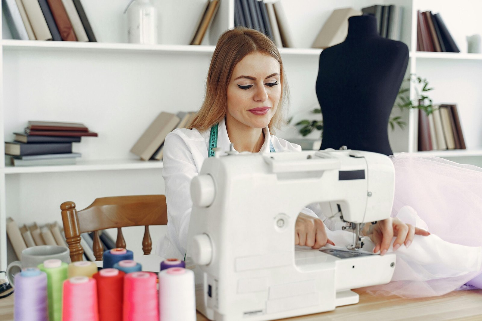 Woman sewing in a creative studio using a sewing machine, focusing on fashion design.