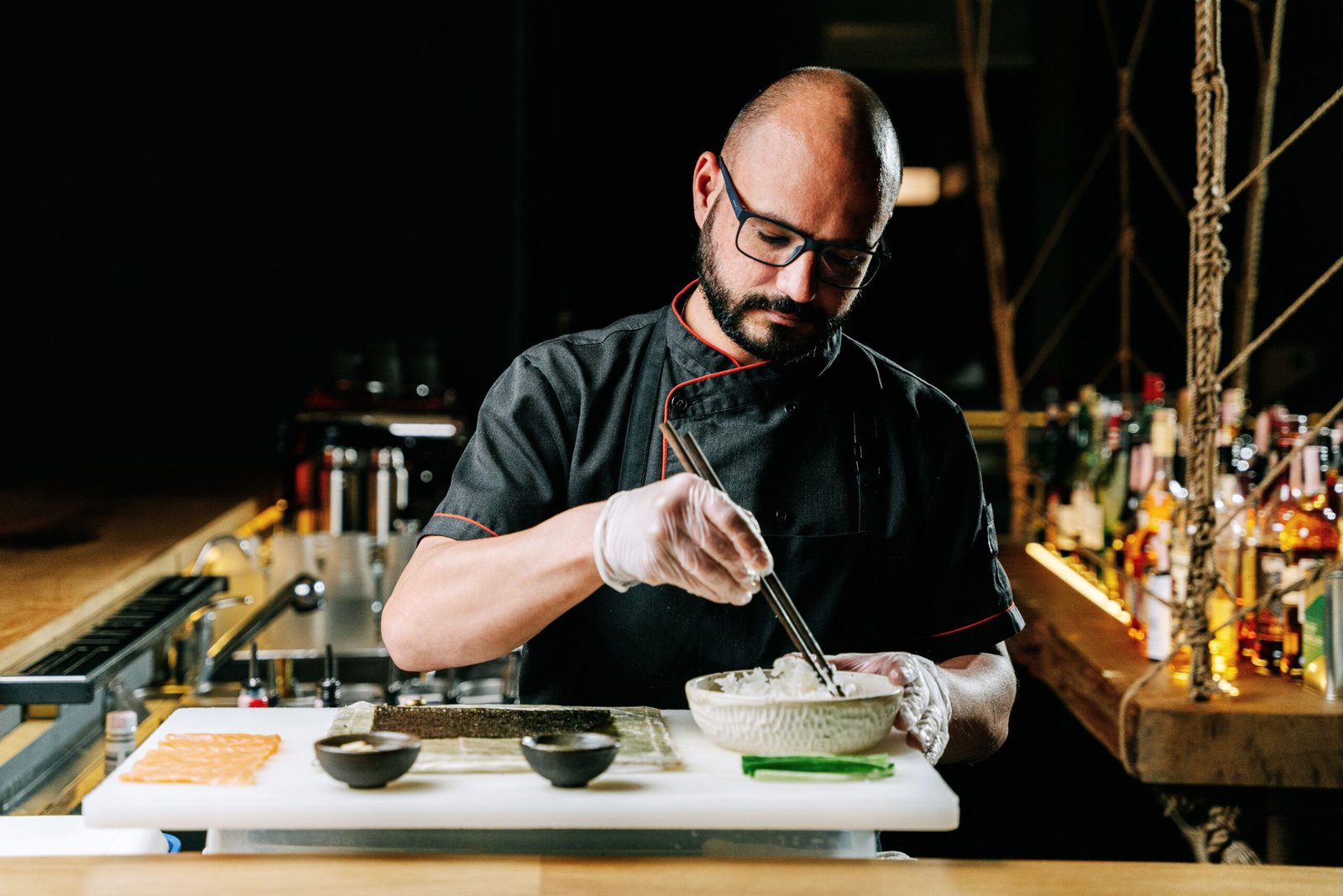 Skilled chef carefully crafting sushi with precision and art in a contemporary kitchen setting.