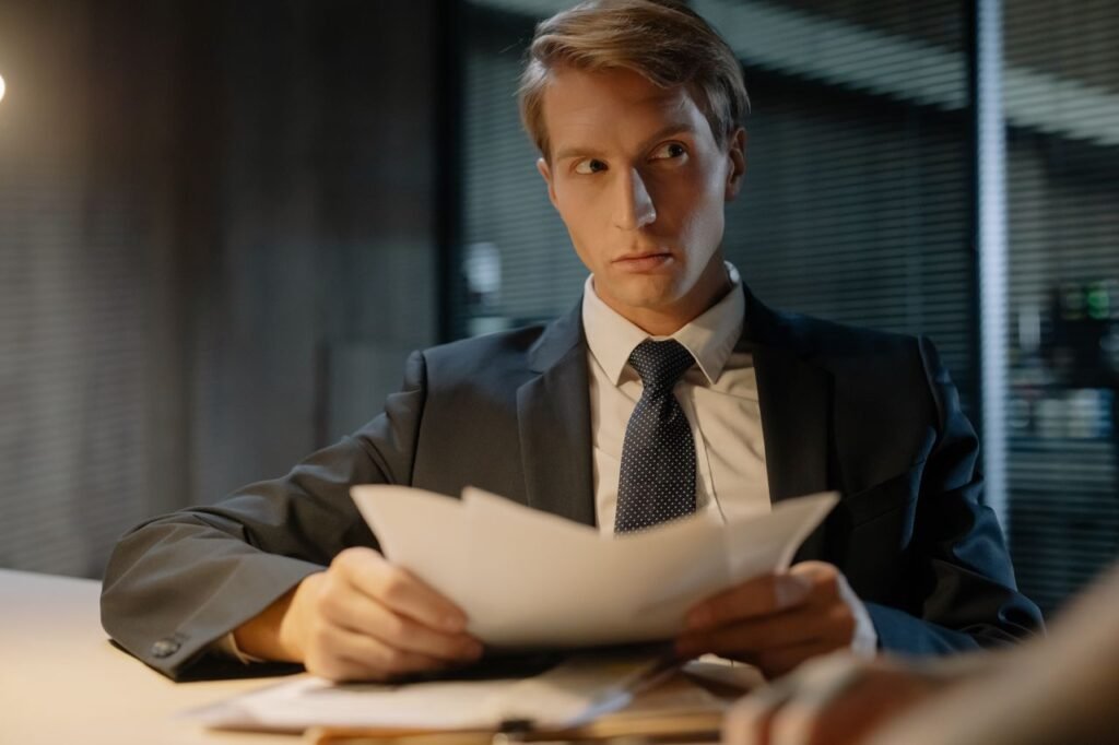 Como Pedir Demissão da Forma Certa: Guia Completo para Sair do Emprego Sem Prejudicar sua Carreira Businessman in suit reviews documents at a desk in a modern office setting.