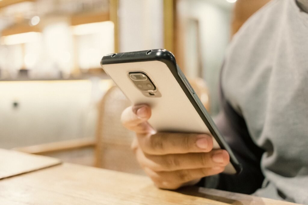 A person using a smartphone in a modern indoor setting, emphasizing technology.