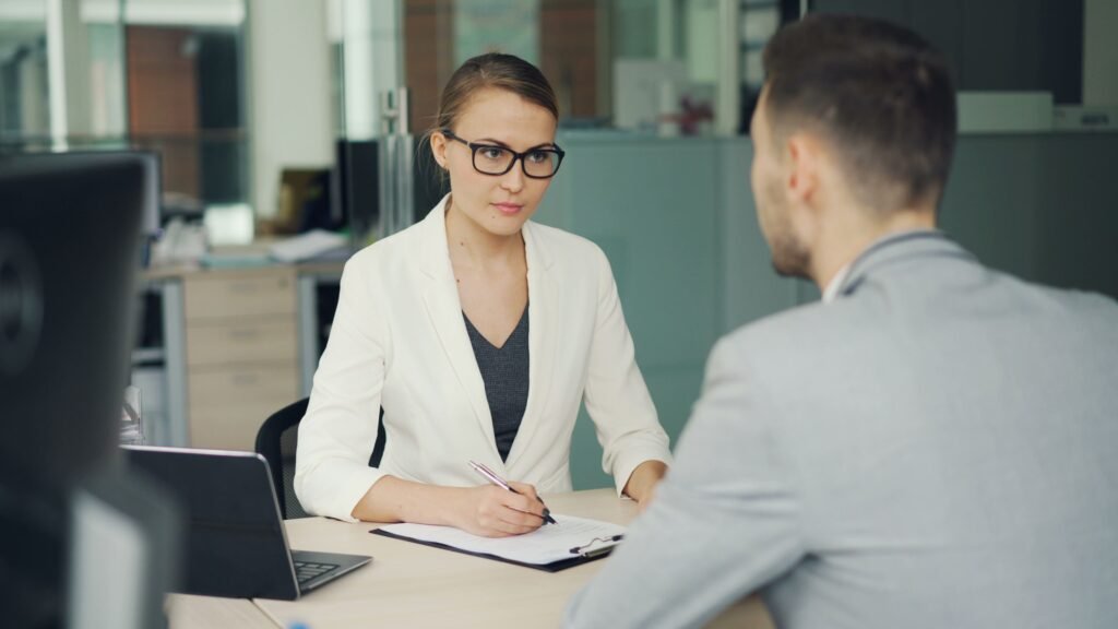 Como Responder “Qual é Sua Pretensão Salarial?” na Entrevista Two professionals in a serious business meeting at a modern office setting.