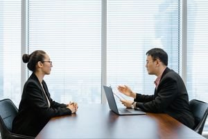 Two businesspeople engaged in a discussion during a professional meeting in an office setting.