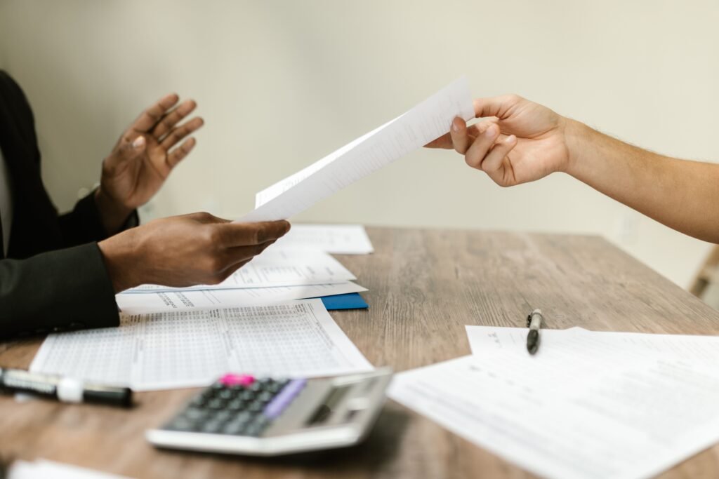 Como Pedir Demissão de Forma Profissional e Preservar sua Carreira Two professionals exchanging documents in a corporate setting, emphasizing collaboration and paperwork.