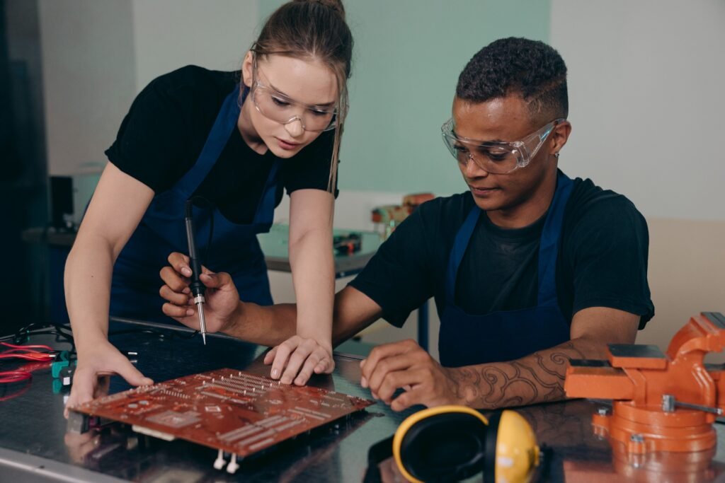 Two engineers collaborate on a circuit board, demonstrating teamwork in technical environments.